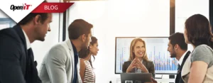 A team in a business meeting discussing software usage metrics, with a woman presenting audit data on a screen—representing Open iT's solution to stop the $500K software license audit drain.