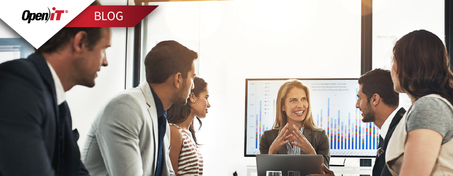 A team in a business meeting discussing software usage metrics, with a woman presenting audit data on a screen—representing Open iT's solution to stop the $500K software license audit drain.