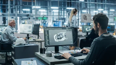 Image of man on his workstation, working on a 3d model of a vehicle part.