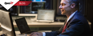 a professional in a suit working on a laptop in a control room environment with multiple monitors. represents open it’s software license inventory management, emphasizing monitoring, tracking, and optimization of software licenses for enterprise use.