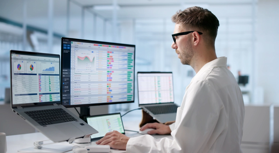 Engineer reviewing software license usage dashboards with charts and reports across multiple monitors